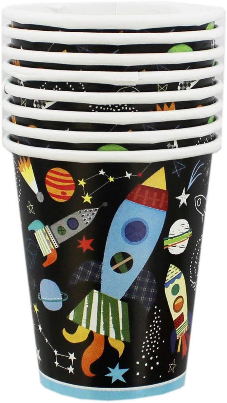 May include: A stack of 9 paper cups with a black background and a colorful space-themed design. The cups feature rockets, planets, stars, and other space-related imagery.
