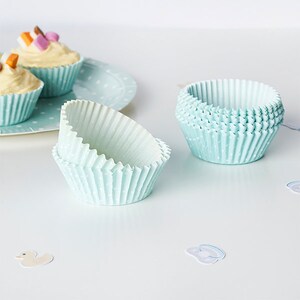 May include: A set of light blue cupcake cases with a white polka dot pattern. The cases are made of paper and are designed to be used in a cupcake tin.