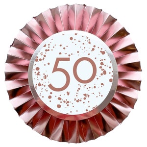 May include: A rose gold paper fan with a white circle in the center. The circle has a rose gold splatter pattern and the number 50 in the center.