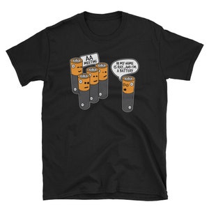 May include: Black t-shirt featuring a cartoon design of AA batteries. One battery says, "Hi my name is Ray...and I'm a battery." The other batteries are at an "AA Meeting."