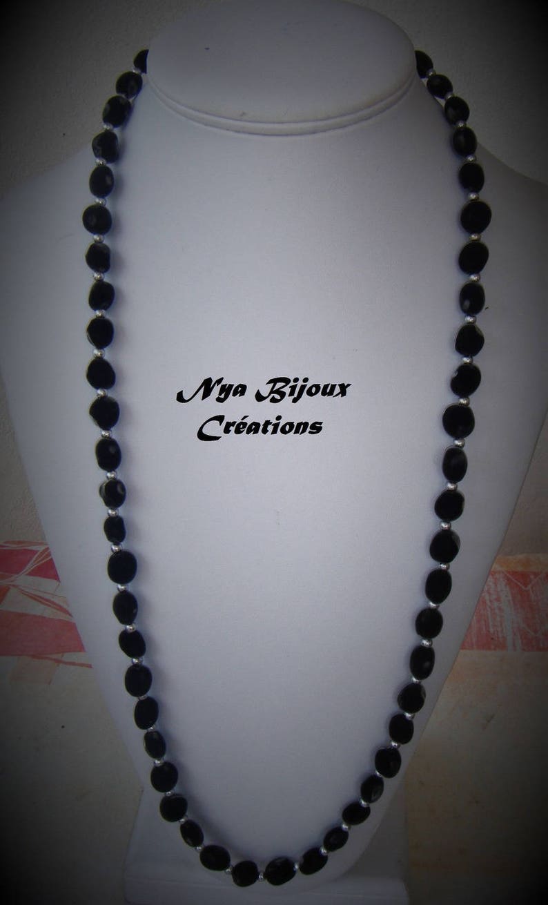 May include: A black beaded necklace with silver accents. The necklace is displayed on a white mannequin bust. The text "Nya Bijoux Creations" is visible on the bust.
