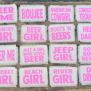 May include: A set of 12 pink and white fabric patches with various sayings related to beer, country, and girls. The patches have a frayed edge and are perfect for adding a touch of personality to clothing, bags, or other accessories.