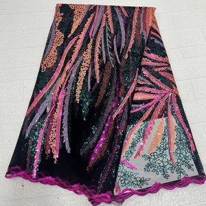 May include: Black fabric with a sequined design featuring pink, orange, and green feather-like patterns. The fabric has a scalloped edge in a bright pink color. The sequins create a shimmering effect, suitable for evening wear or special occasion garments.