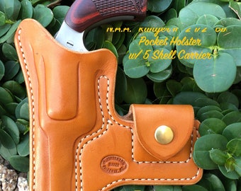 Könnte beinhalten: Ein hellbraunes Leder-Taschenholster mit passendem Patronenhalter, das einen Revolver mit Holzgriff hält. Das Holster ist mit weißem Faden genäht und trägt den Text "N.A.A. Kunyer 2 1/2" und "Pocket Holster w/5 Shell Carrier".