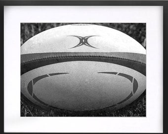 May include: A black and white photograph of a rugby ball with a black and white design on it.