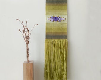 Green woven wall hanging with with embroidered flowers. Narrow, long, vertical woven art. Gallery wall decoration. Flower embroidery art.