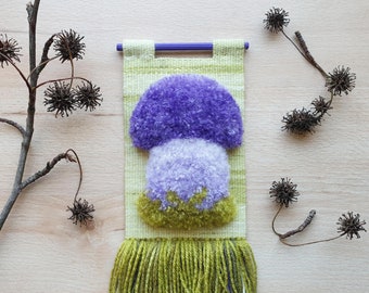 Mini green and purple woven wall hanging with fluffy mushroom.  Handmade, very small, narrow mushroom wall decor for forest themed room.