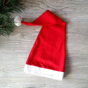 May include: A red Santa hat with a white pom-pom on top and a white trim around the bottom.
