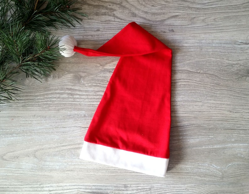May include: A red Santa hat with a white pom-pom on top and a white trim around the bottom.