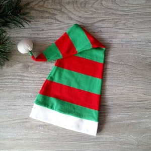 May include: A red and green striped elf hat with a white pom-pom on top.