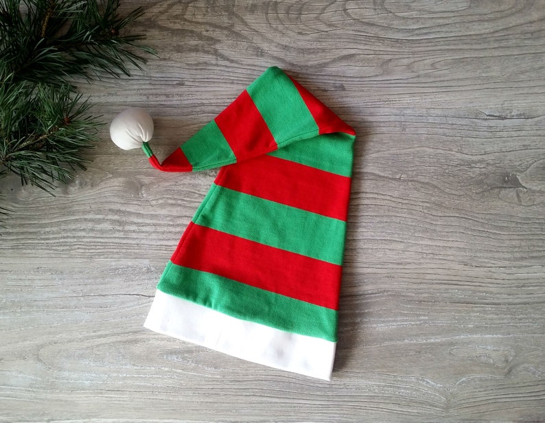 May include: A red and green striped elf hat with a white pom-pom on top.