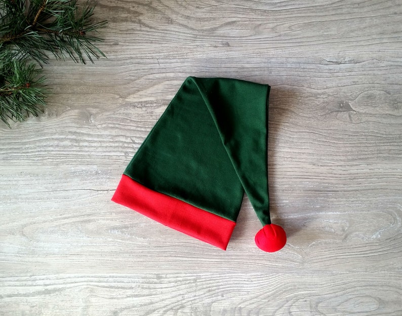 May include: A green elf hat with a red trim and a red pom-pom on the end.