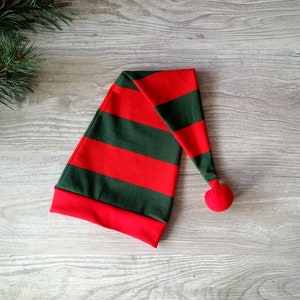 May include: A red and green striped elf hat with a red pom-pom on top.