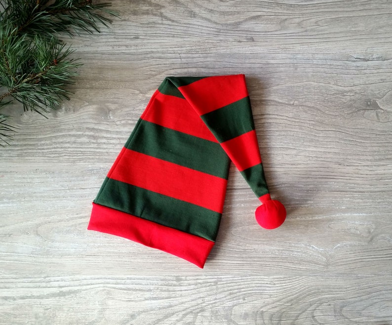 May include: A red and green striped elf hat with a red pom-pom on top.