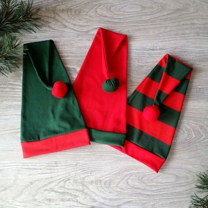 May include: Three elf hats in red and green. One hat is solid red, one is solid green, and one is striped red and green.