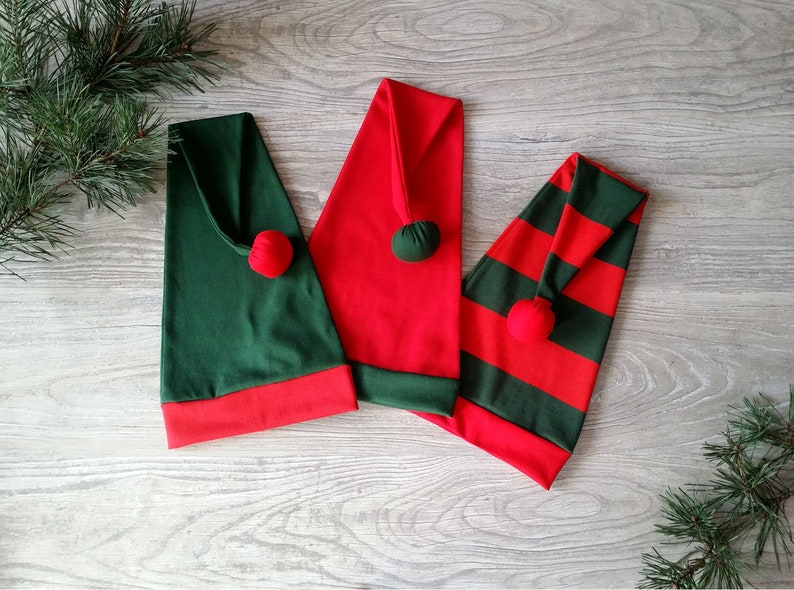 May include: Three elf hats in red and green. One hat is solid red, one is solid green, and one is striped red and green.