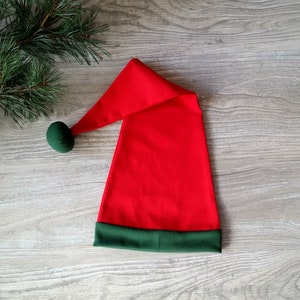 May include: A red and green Santa hat with a green pom-pom on top.
