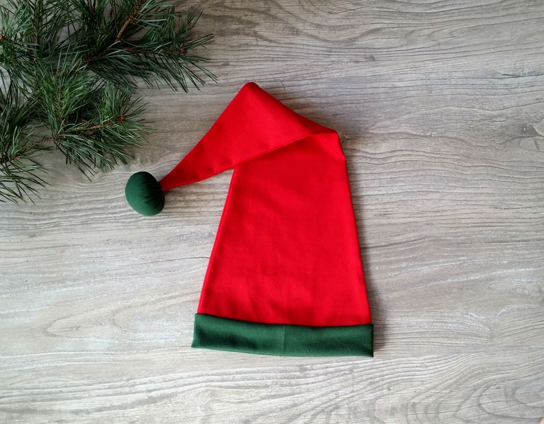 May include: A red and green Santa hat with a green pom-pom on top.