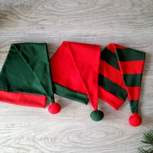 May include: Three elf hats with red and green fabric. The hats have a pointed tip and a pom-pom on the end.