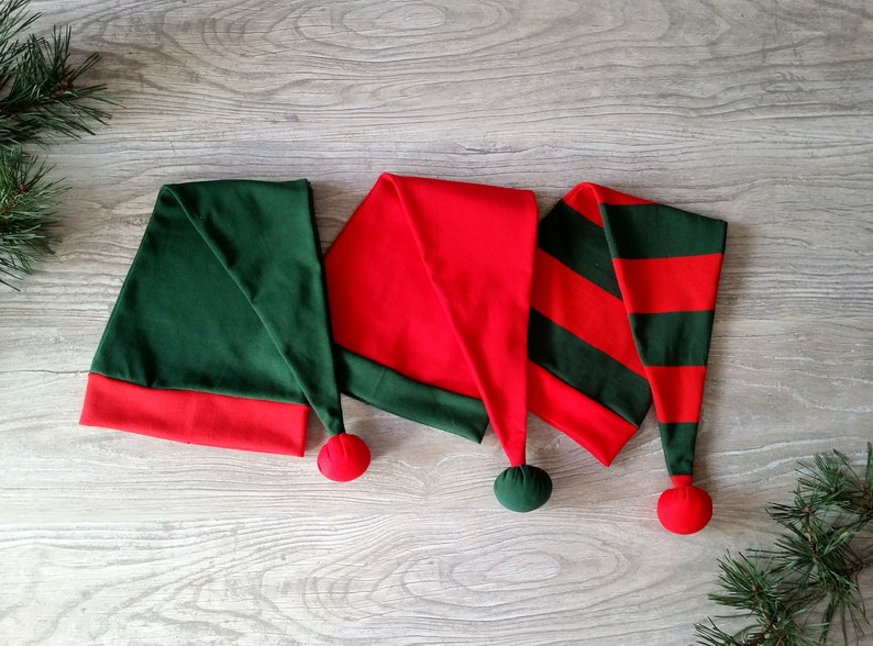 May include: Three elf hats with red and green fabric. The hats have a pointed tip and a pom-pom on the end.