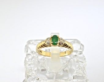 May include: A gold ring with a green emerald gemstone and small diamonds on the band.