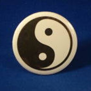 May include: A black and white yin yang symbol on a round button.