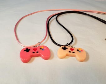 VIDEO GAME CONTROLLERS Set of 2 Charms Pendant Necklaces. Lavender charm on purple rope style necklace; hot pink charm on black necklace.