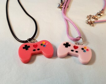 VIDEO GAME CONTROLLERS Set of 2 Charms Pendant Necklaces. Lavender charm on purple rope style necklace; hot pink charm on lavender necklace.