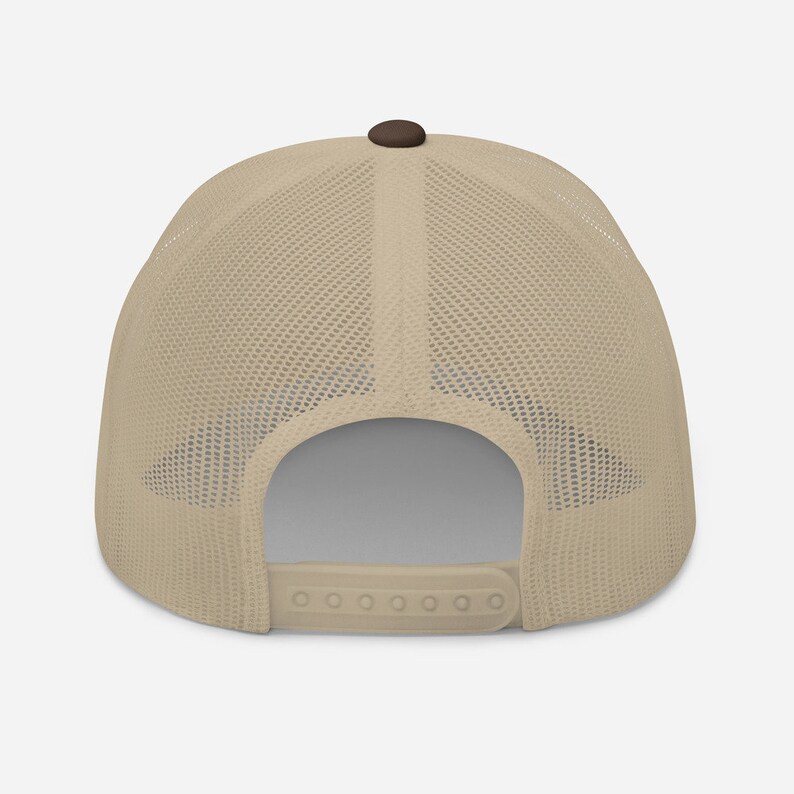 May include: A beige and brown mesh trucker hat with a brown button on top. The hat has a plastic adjustable strap in the back.