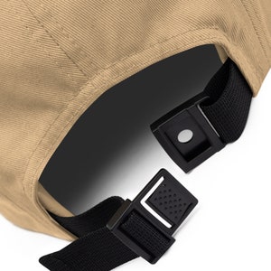 May include: A tan baseball cap with a black adjustable strap and buckle closure.