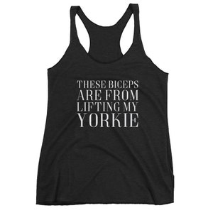 May include: Black racerback tank top with white text that reads "These biceps are from lifting my yorkie".