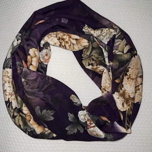 Könnte beinhalten: Ein lilafarbener Infinity-Schal mit einem Blumendruck mit beige und grünen Blumen.