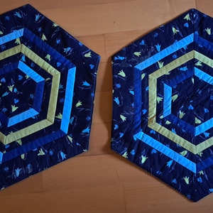 Könnte beinhalten: Zwei sechseckige blaue, grüne und gelbe Stoff-Platzsets mit geometrischem Muster.