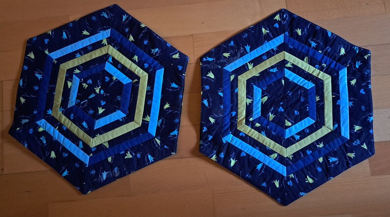 K&ouml;nnte beinhalten: Zwei sechseckige blaue, gr&uuml;ne und gelbe Stoff-Platzsets mit geometrischem Muster.