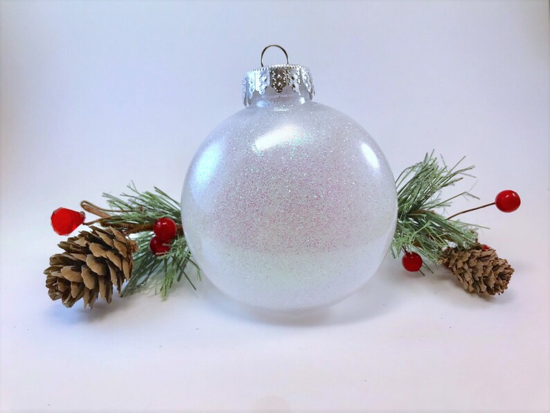 K&ouml;nnte beinhalten: Ein wei&szlig;er, schimmernder Weihnachtsbaumschmuck mit silberner Spitze.