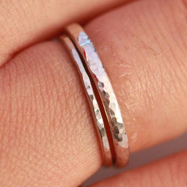 May include: Two silver hammered stacking rings worn on a finger.
