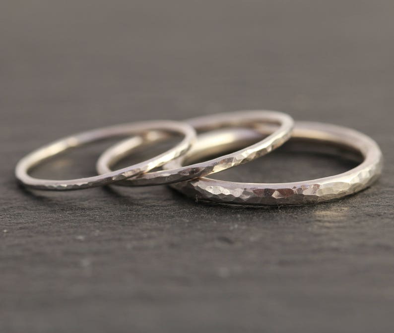 May include: Three silver hammered stacking rings. The rings are thin and delicate, with a textured surface.