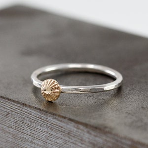 Puede incluir: Un anillo de plata con acabado martillado y un disco de oro con un diseño texturizado.