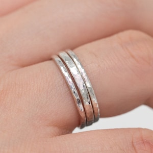 Op de afbeelding: Drie zilveren gehammerde stapelringen gedragen op een vinger.