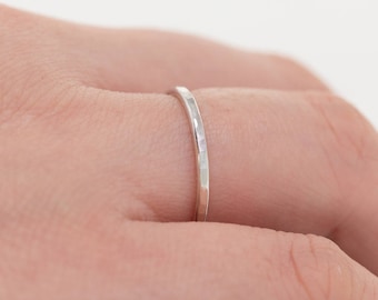 May include: A thin silver band ring with a hammered texture.