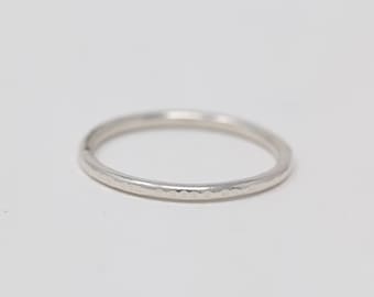 May include: A simple silver band ring with a hammered texture.