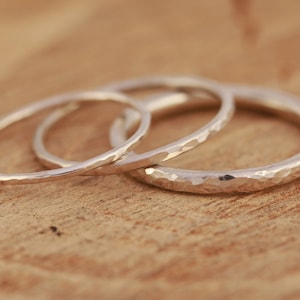 May include: Three silver hammered stacking rings. The rings are all different sizes and are stacked on top of each other.