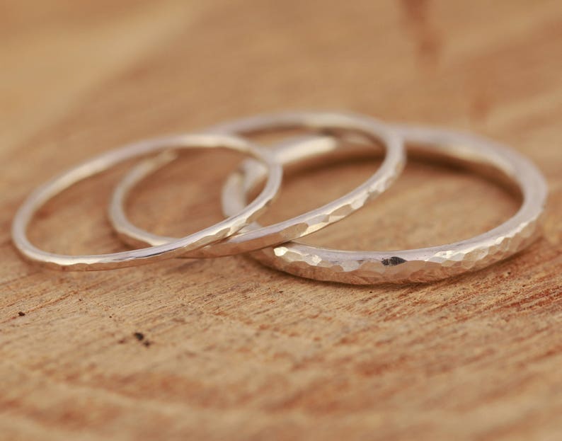 May include: Three silver hammered stacking rings. The rings are all different sizes and are stacked on top of each other.