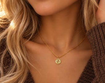 May include: A gold-toned necklace featuring a delicate chain and a small, circular pendant. The pendant displays the Cancer zodiac symbol, which consists of two curved lines resembling a crab, centered within a thin, circular gold-toned frame.