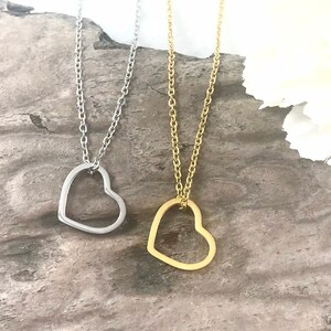 Pu&ograve; includere: Due delicate collane con ciondoli a forma di cuore aperto. Una collana ha un ciondolo a forma di cuore argentato e l'altra ha un ciondolo a forma di cuore dorato.