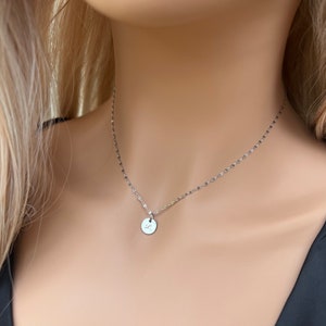 May include: A silver chain necklace with a small round pendant featuring a cursive letter 'S'.