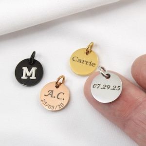 Peut inclure: Quatre pendentifs ronds personnalisés en noir, or, or rose et argent. Les pendentifs comportent des initiales, des noms et des dates gravés. Chaque pendentif a une petite boucle pour l'attacher à un collier ou un bracelet. Les pendentifs sont présentés sur fond blanc.