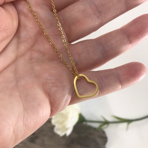 Pu&ograve; includere: Una collana a catena dorata con un delicato ciondolo a forma di cuore aperto.