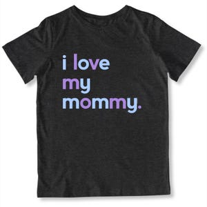 May include: Dark gray t-shirt with the phrase "i love my mommy" printed in light blue, purple, and lavender. The shirt is a crew neck and has short sleeves.