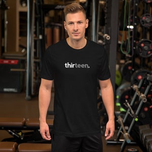 May include: A black short-sleeved t-shirt with the word "thirteen." printed in white on the front.